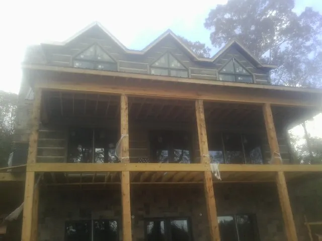 Dormers and porch framing on a large log home under construction — Roof Coating work by our crew in Glen Flora