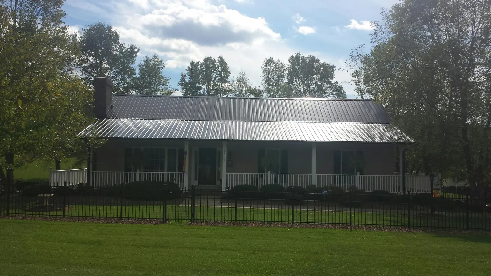 Gray metal roof on a brick ranch with a full width front porch — Gutter Guard Installation work by our crew in Glen Flora