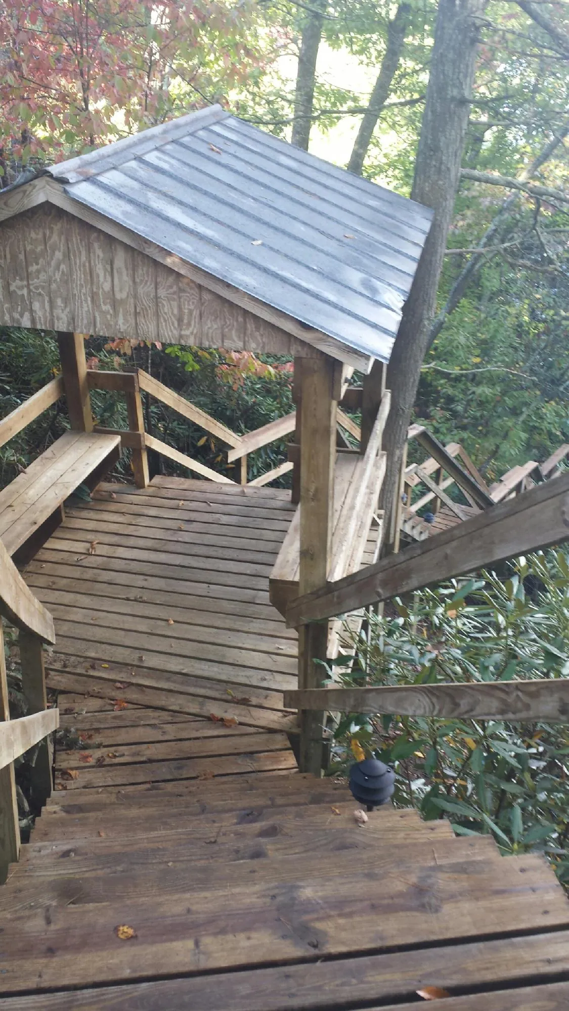 Metal roofed shelter over wooden steps on a wooded walkway — Skylight Repair & Installation work by our crew in Glen Flora