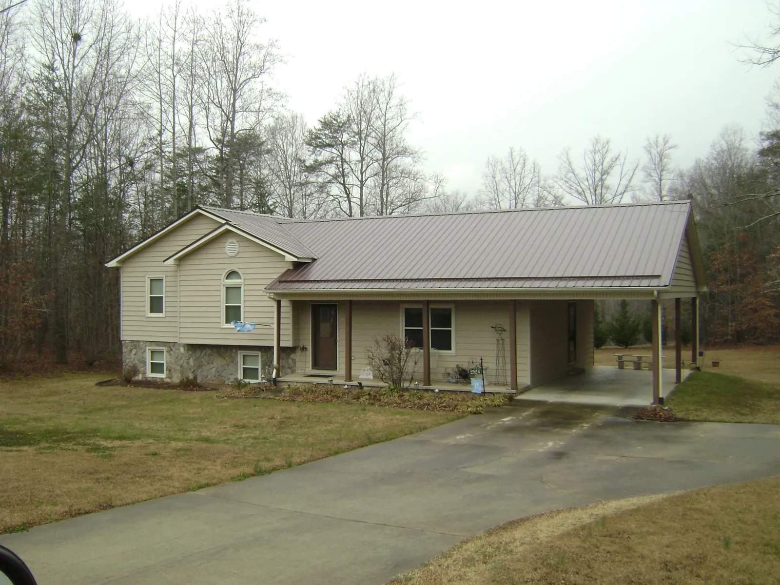 Brown metal roof on a tan split level home with an attached carport in Glen Flora