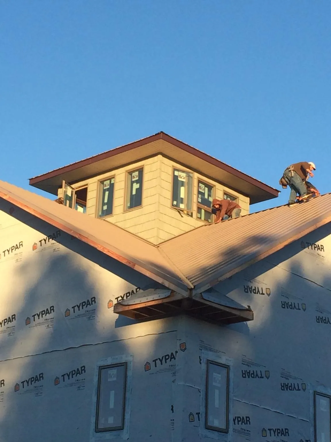 Roofers working around a rooftop cupola on a new metal roof at sunset — Roof Waterproofing in Glen Flora by Roofing Brothers